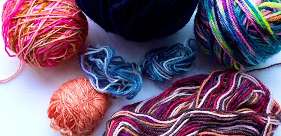 Multicoloured balls of yarn ranging from dark blue to vibrant pink